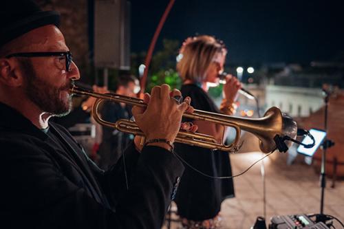 Musicista suona la tromba e donna canta al microfono in un evento in Italia